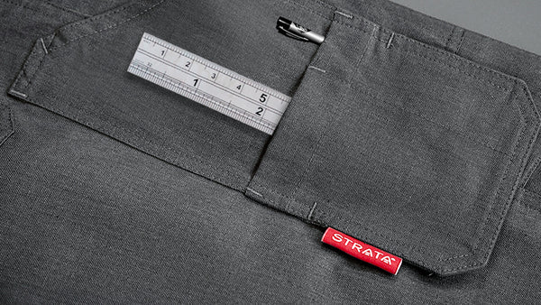 A grey pocket of a PPE trouser is shown in which a ruler and pen sits. A red Strata label is on the lapel. To support information about ASTM F1506