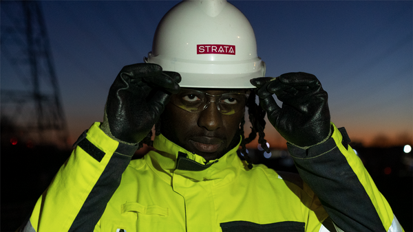 A man holds his gloved hands up to a white helmet and clear visor. The sun is setting. Image to demonstrate EN ISO 14116 - protection against flame.